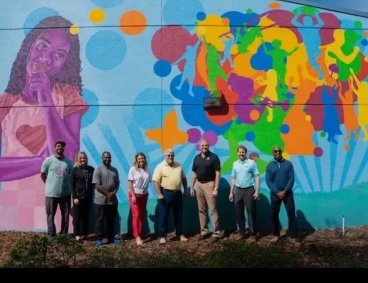 Community initiative team in front of a community mural
